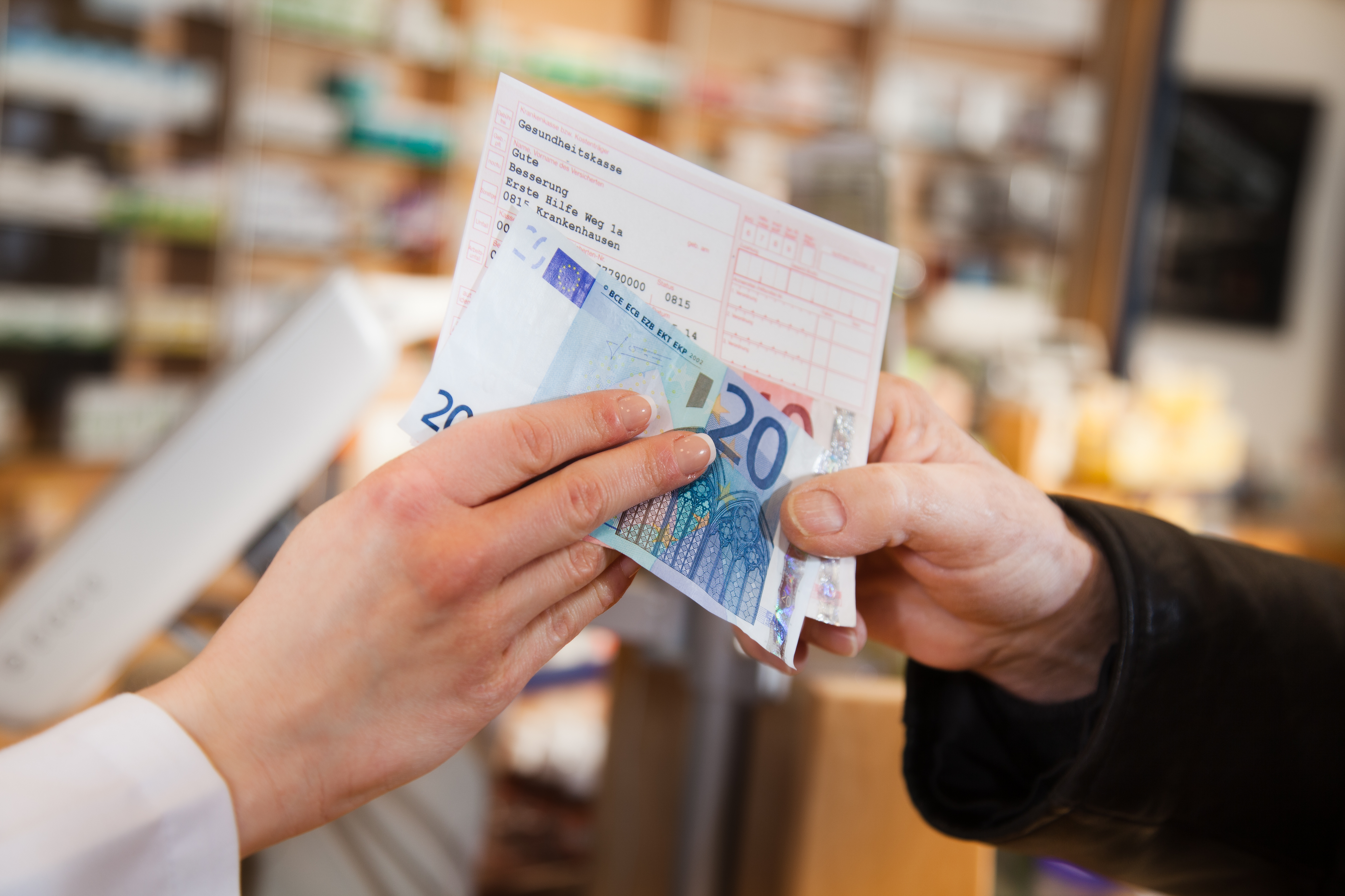 Zwei Hände bei der Übergabe eines Rezeptes und 20 Euro
